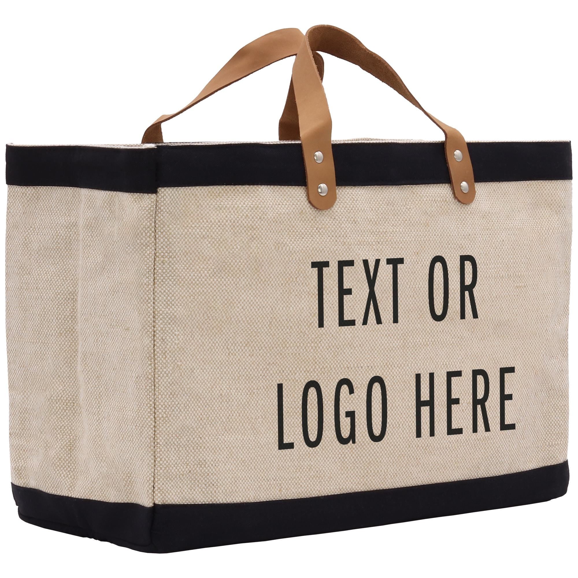 A beige tote bag with black trim and leather handles, featuring the text &quot;Text or Logo Here&quot; printed on it.