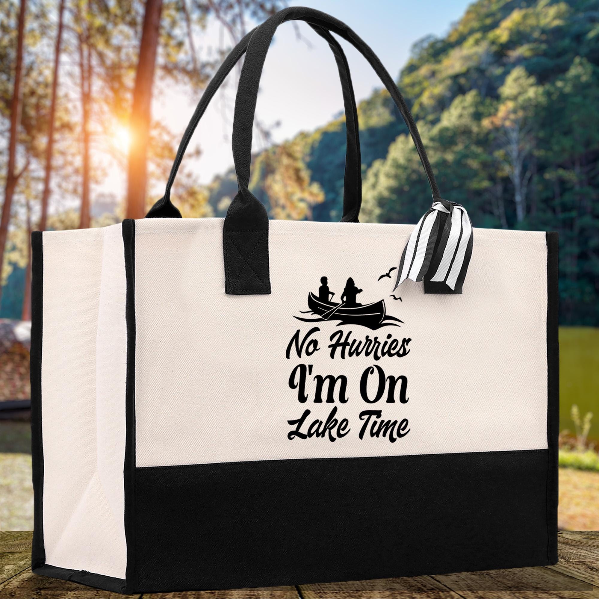 A white tote bag with a black and white graphic design and text printed on it, placed on a wooden surface with a natural outdoor background.