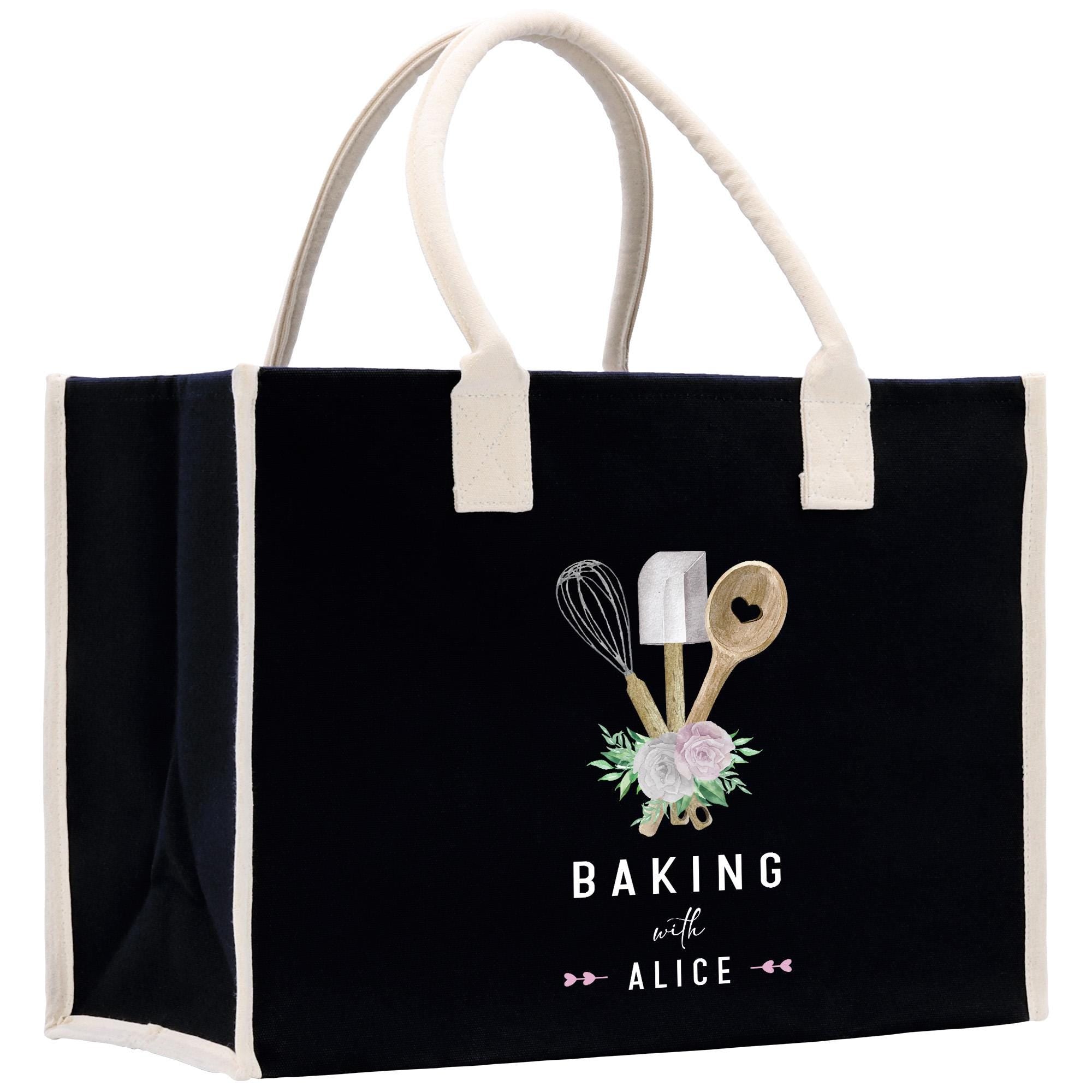 A black tote bag with a white handle and trim, featuring a graphic design of baking utensils and flowers.