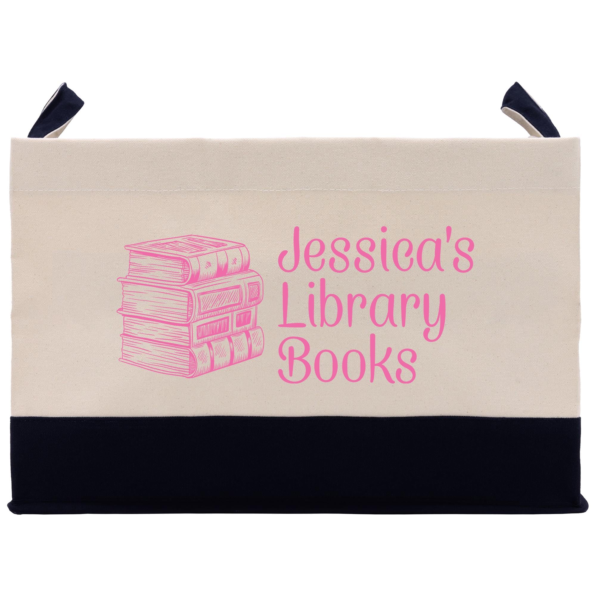 A beige tote bag with a black trim, featuring a pink illustration of a stack of books and the text &quot; Jessica&#39;s Library Books&quot; printed on it.