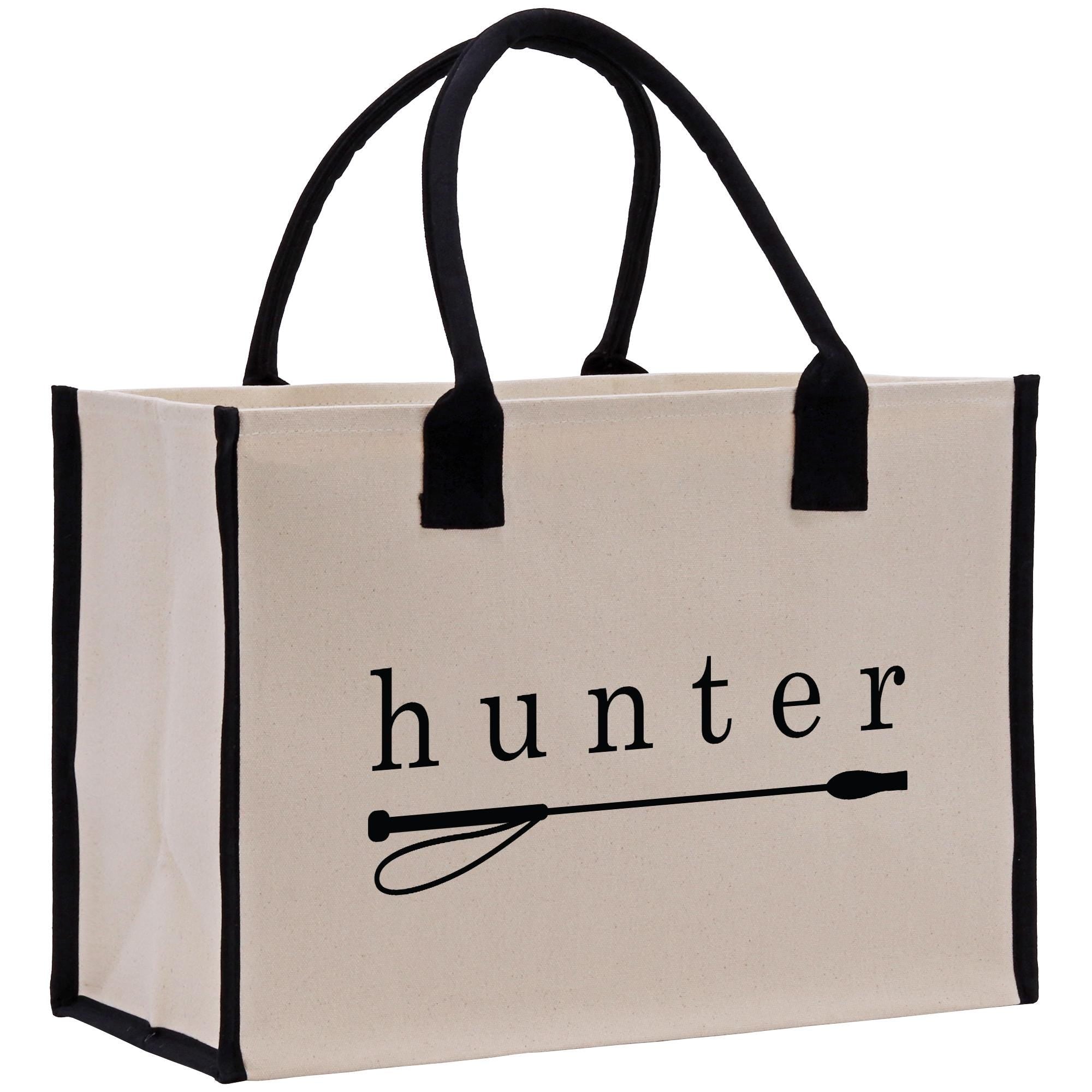 A beige canvas tote bag with black handles and trim, featuring the word &quot;hunter&quot; printed on it.