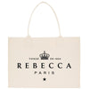 a beige tote bag with the text "REBECCA PARIS" printed on it.