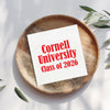 A white paper with red text is placed on a wooden plate, surrounded by green leaves.