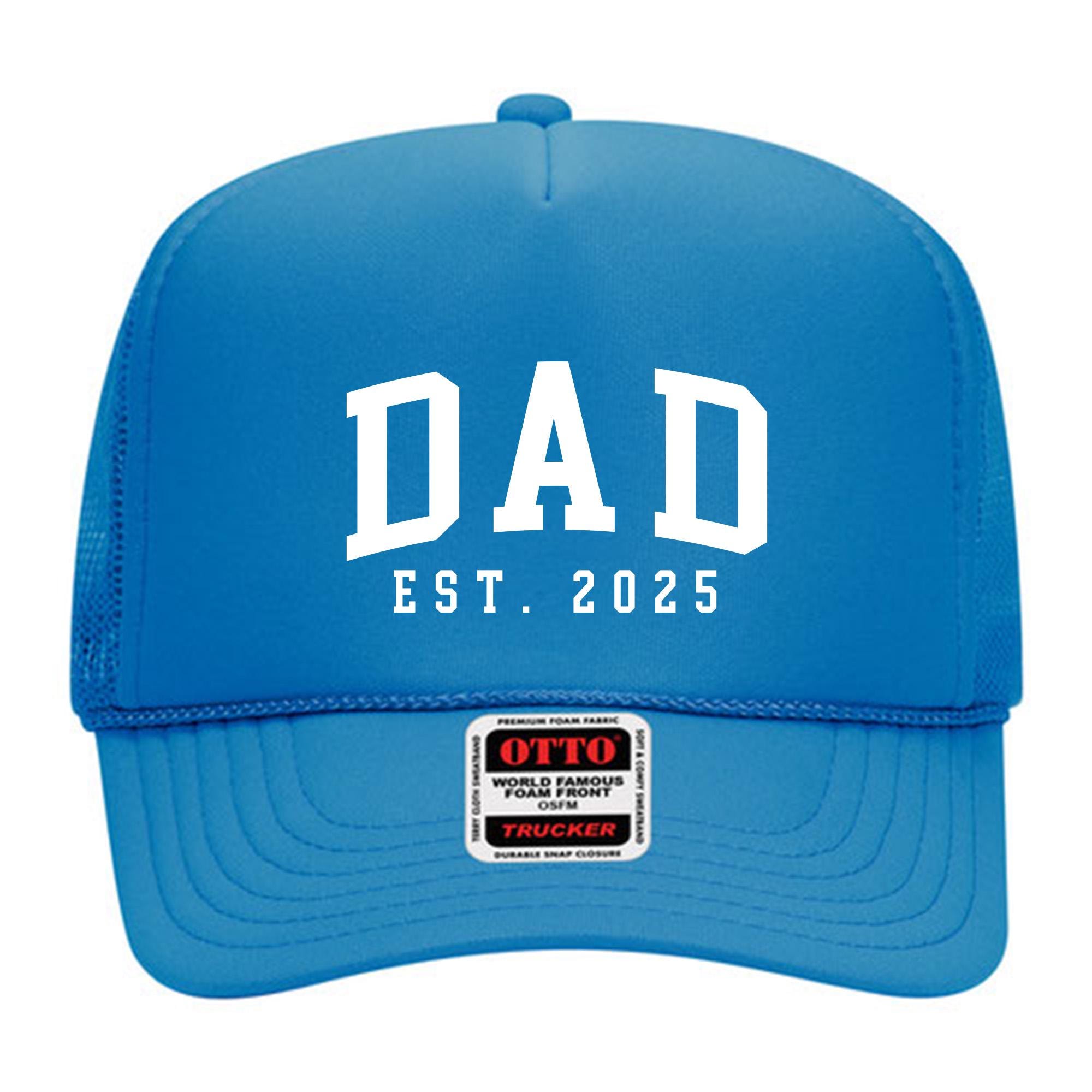 A blue baseball cap with the text &quot;DAD EST. 2025&quot; printed on it.