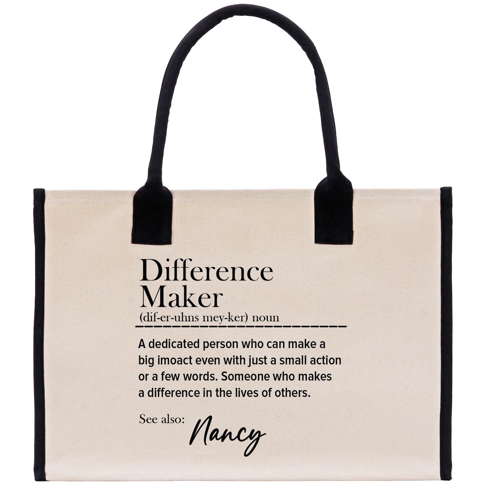 a beige tote bag with black handles and a definition of a &quot; Difference Maker&quot; printed on it.