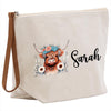 A beige canvas tote bag with a printed design of a cow's head wearing a floral crown and surrounded by flowers. The name "Sara" is written in cursive below the design.