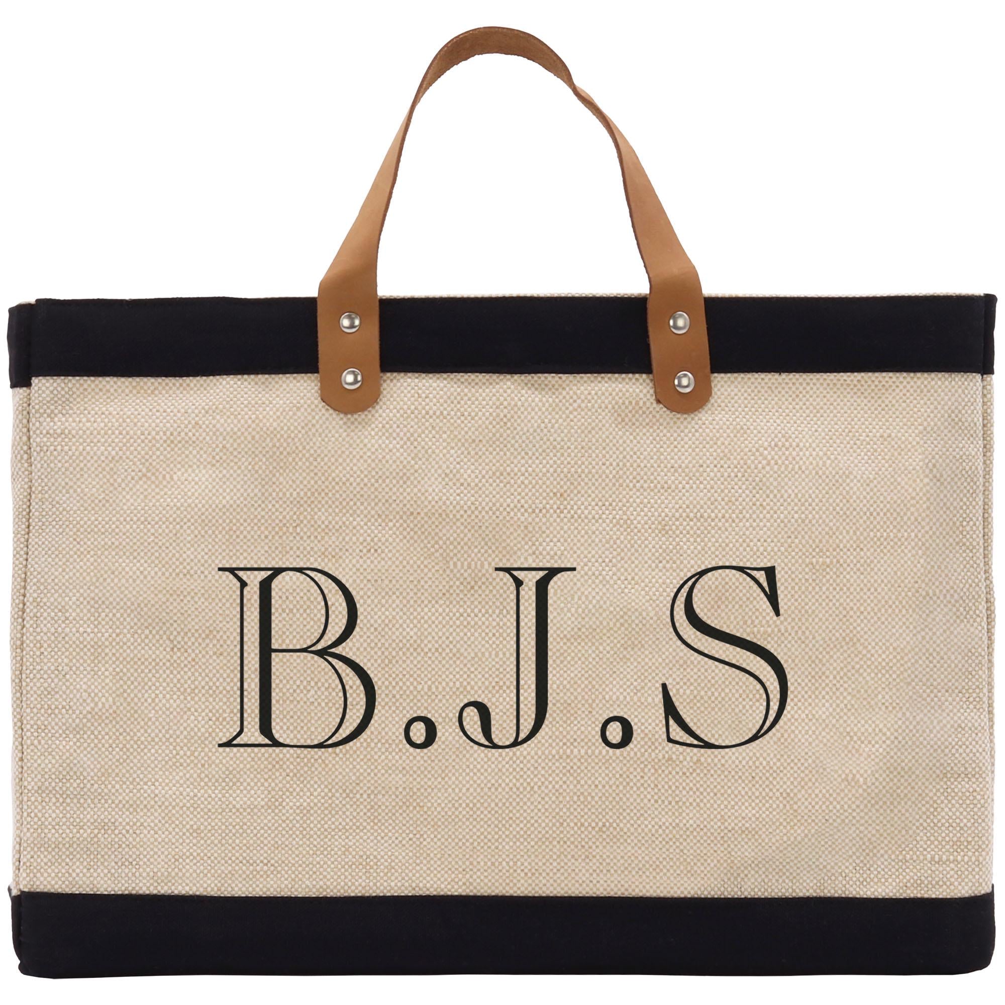 A beige tote bag with a black trim and leather handles. The bag has a monogrammed text on it that reads &quot;B.J.S.&quot;