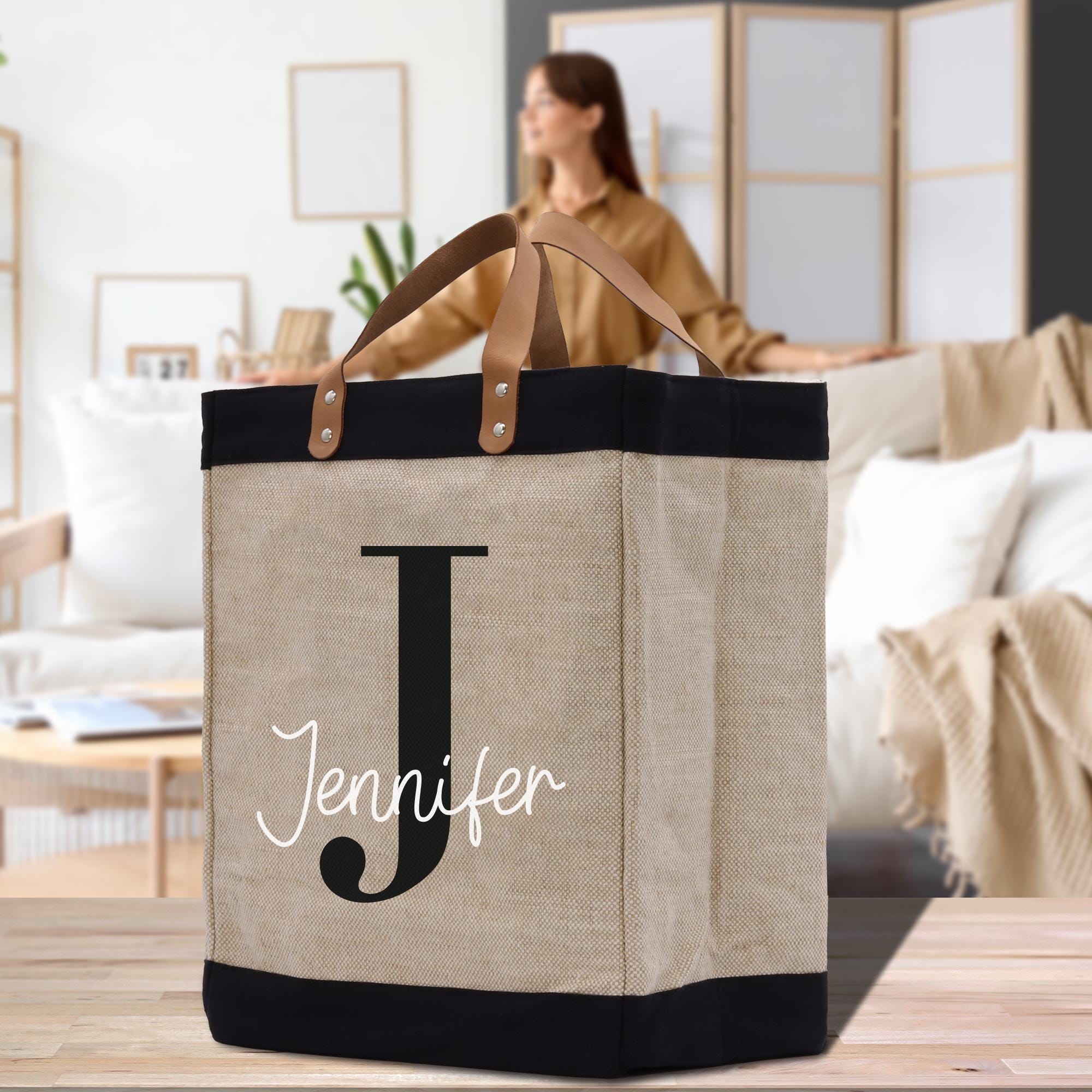 a woman standing behind a jute bag with the letter j on it
