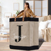 a woman standing behind a jute bag with the letter j on it