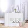 A white tote bag with the text "BRIDE Mrs. Smith" printed on it, along with a matching purse and a dress in the background.