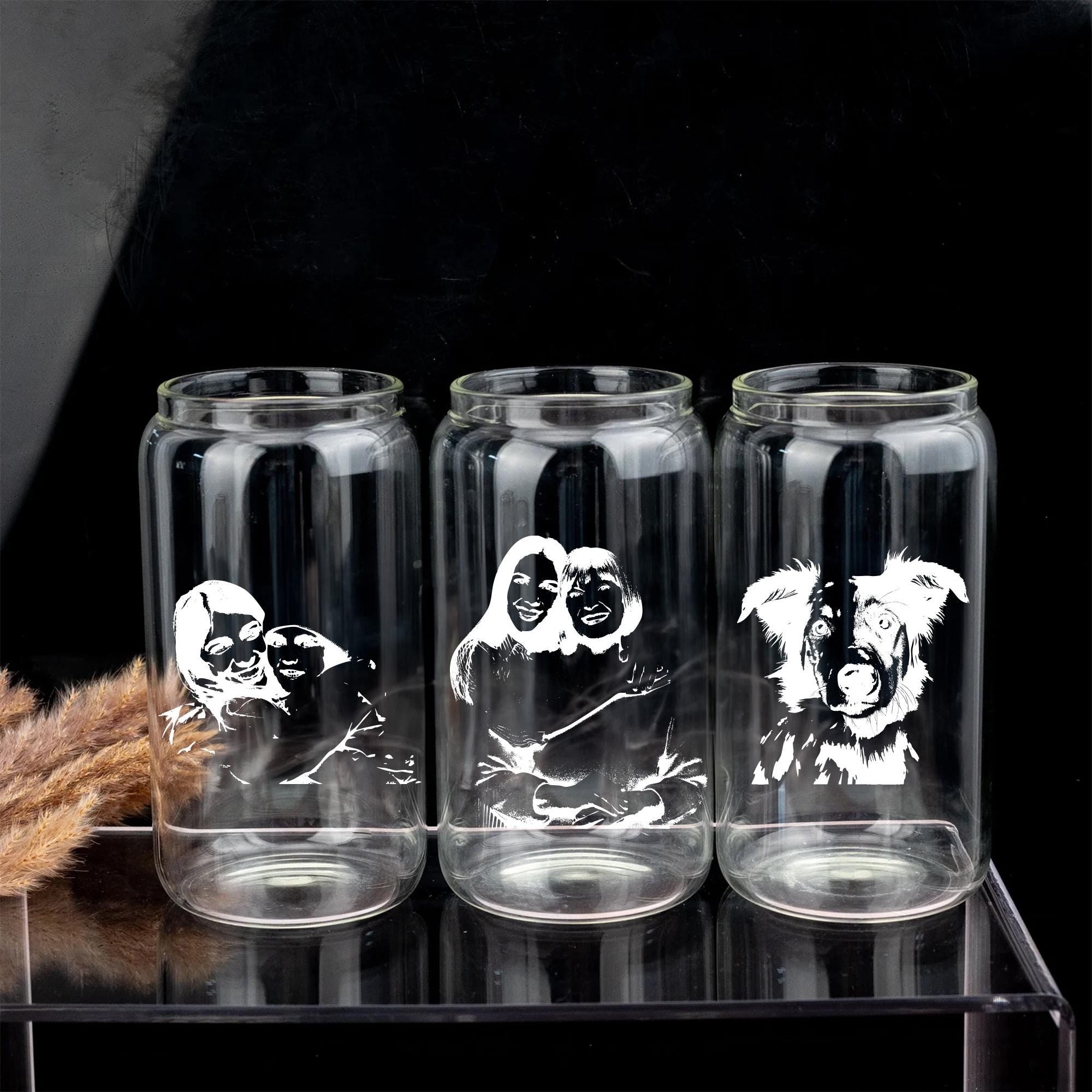 Three clear glass tumblers with black and white illustrations of people and dogs printed on them.
