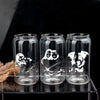 Three clear glass tumblers with black and white illustrations of people and dogs printed on them.