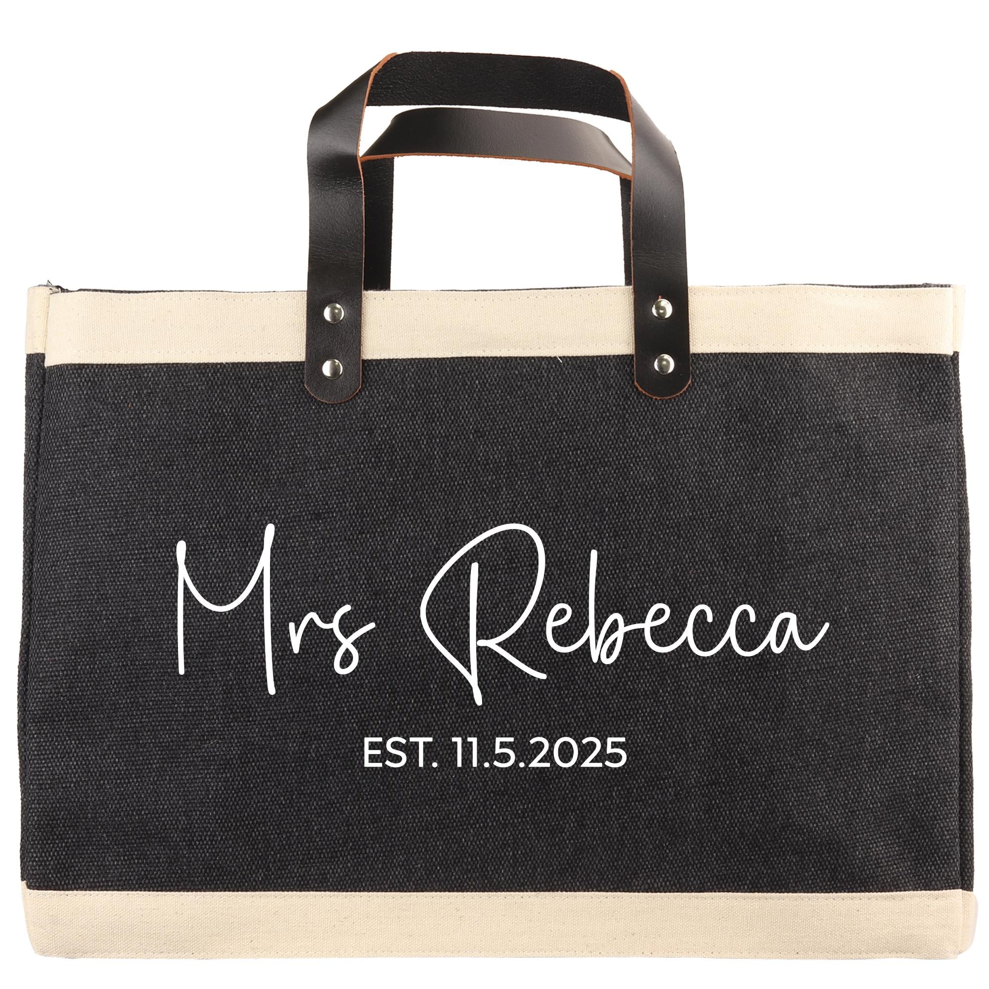 A black and beige tote bag with the text "Mrs Rebecca EST. 11.5.2025" printed on it.