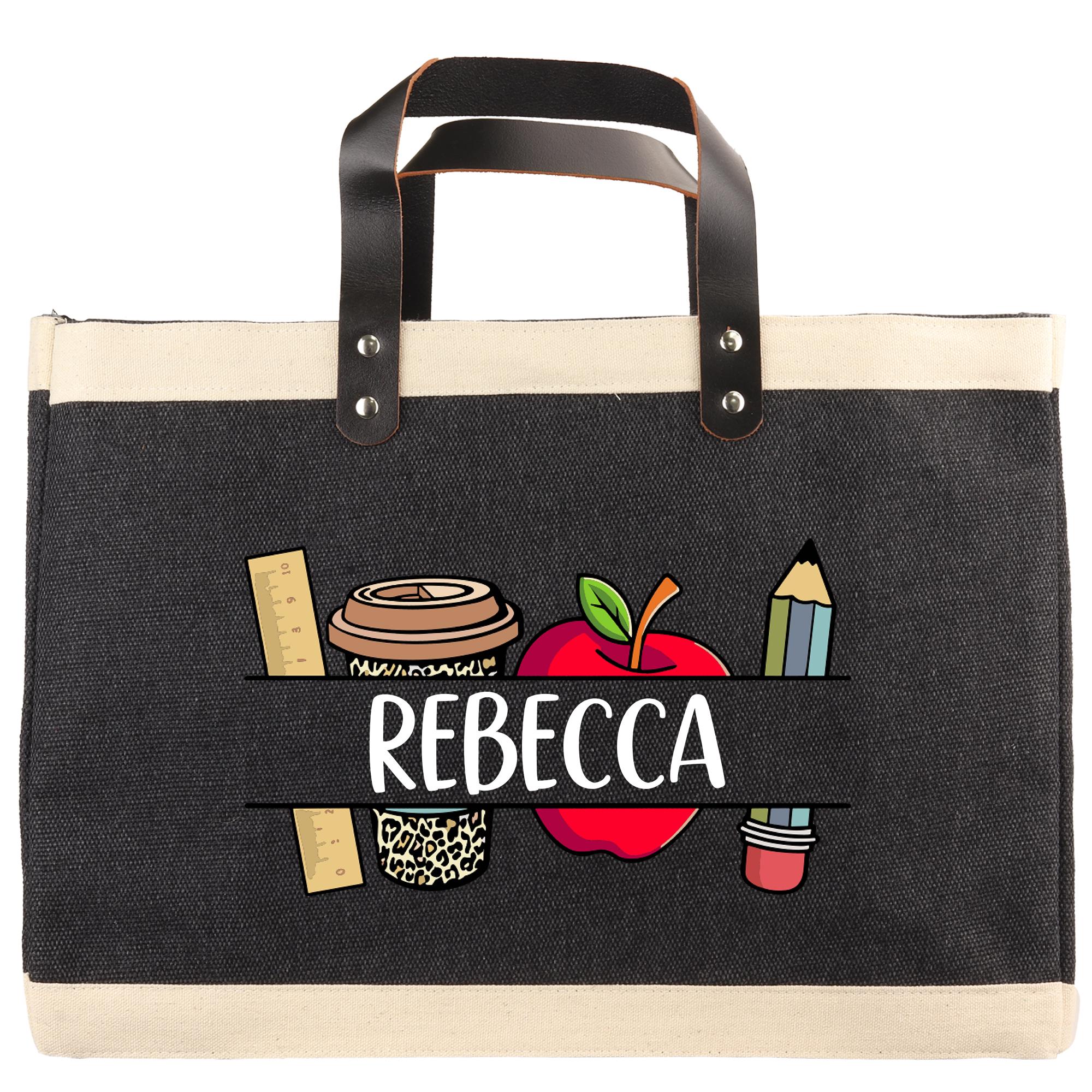 A black tote bag with a printed design on it, featuring a coffee cup, apple, pencil, and ruler. The name "REBECCA" is printed below the design.