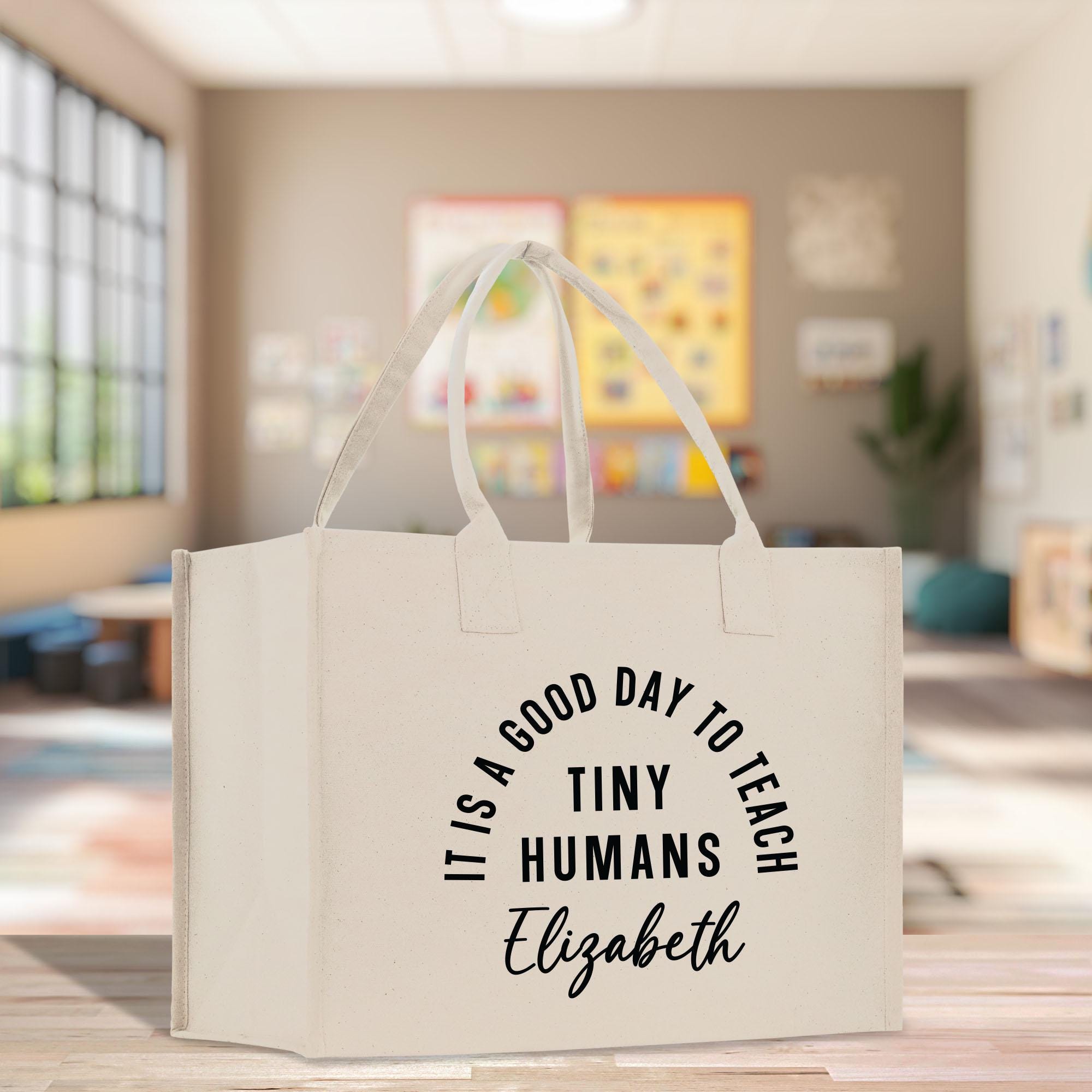 a white bag that says it&#39;s a good day to teach tiny humans el