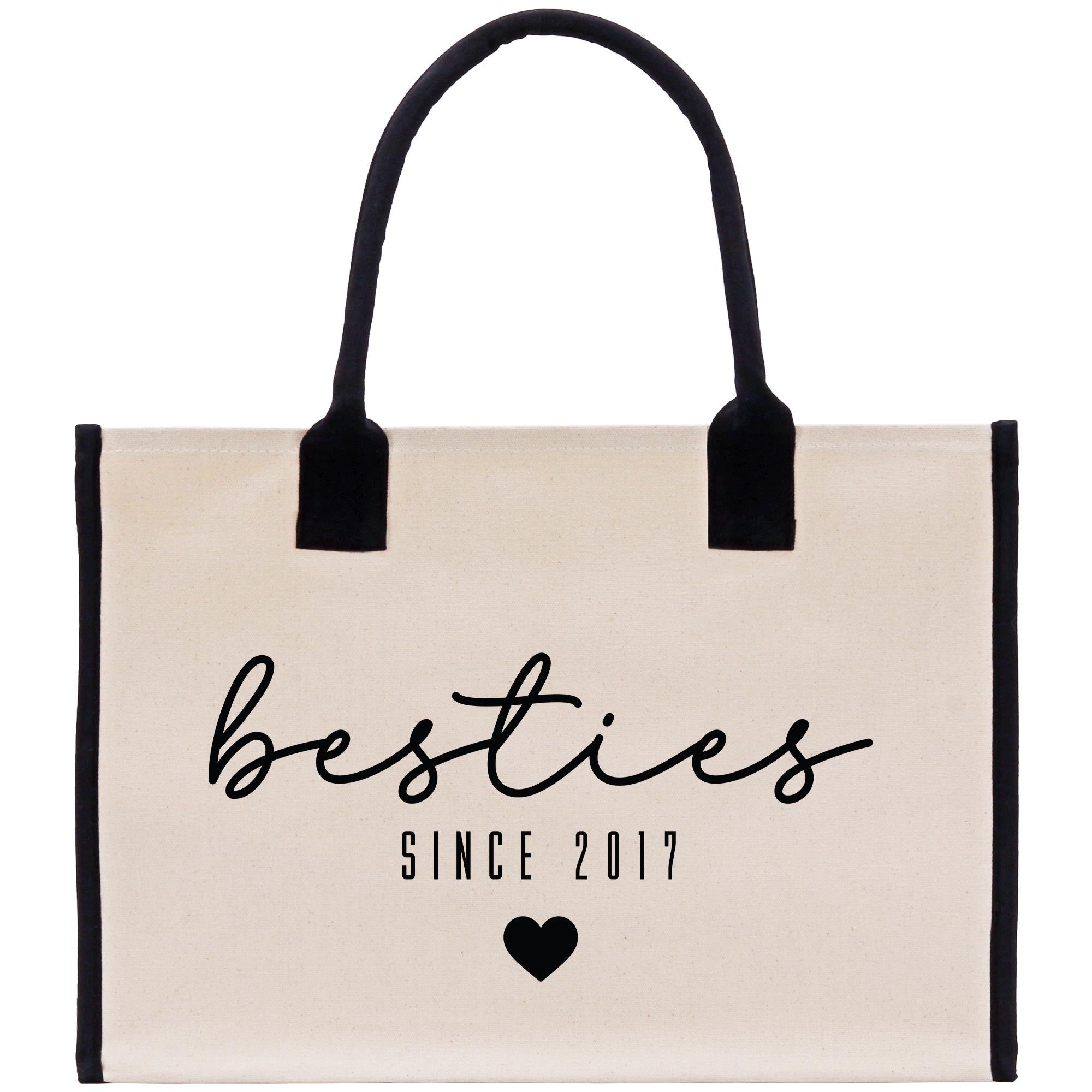 A beige canvas tote bag with black handles and trim, featuring the text &quot;besties&quot; in a cursive font and &quot;SINCE 2017&quot; below it.