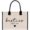 A beige canvas tote bag with black handles and trim, featuring the text "besties" in a cursive font and "SINCE 2017" below it.