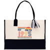 A beige tote bag with a black handle and a black and white striped ribbon attached to it. The bag has a graphic on the front that says 