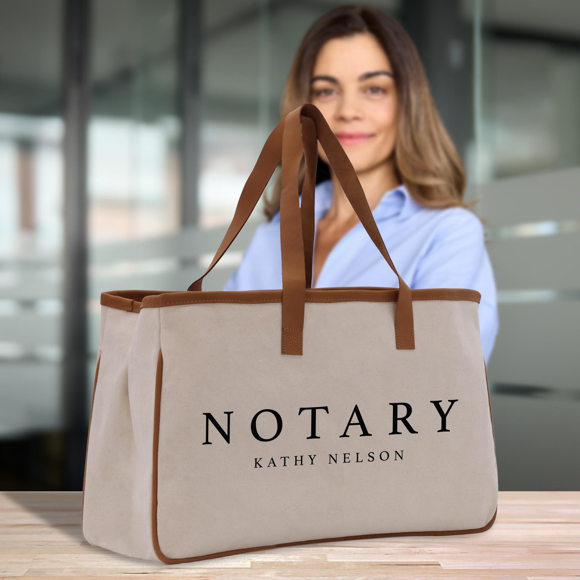 A woman is standing behind a beige tote bag with the word &quot;NOTARY&quot; printed on it.