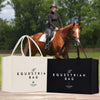 two large bags, one white and one black, placed on a wooden surface. In the background, there is a person riding a horse.