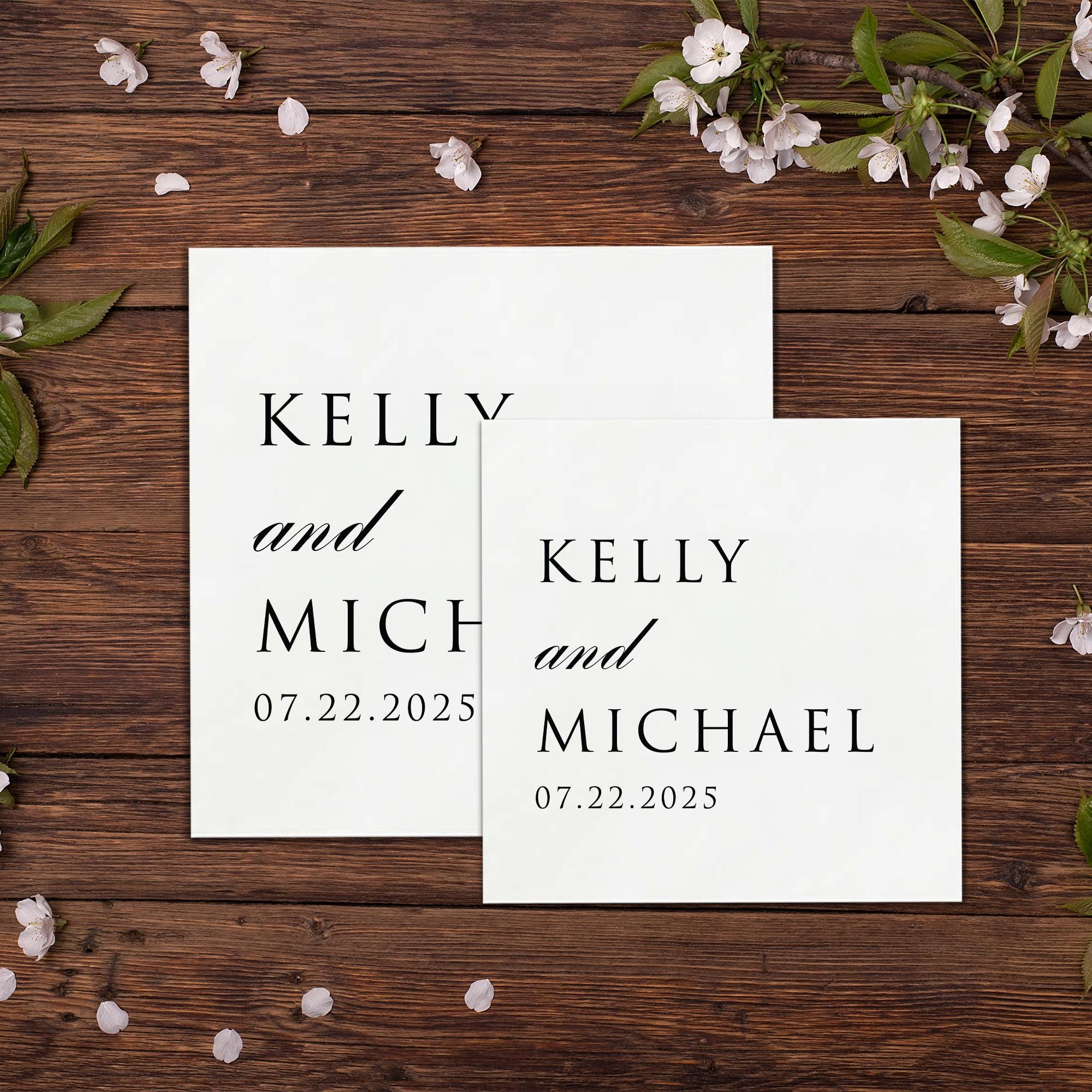 two white square cards with black text, placed on a wooden surface. The text on the cards reads &quot;KELLEY and MICHAEL 07.22.2025&quot;.