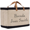 A beige tote bag with black trim and leather handles, featuring personalized text that says "Benda Joan Smith".