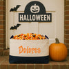 A Halloween-themed scene with a carved pumpkin, a basket filled with candy, and a sign that reads "HALLOWEEN" above a door.