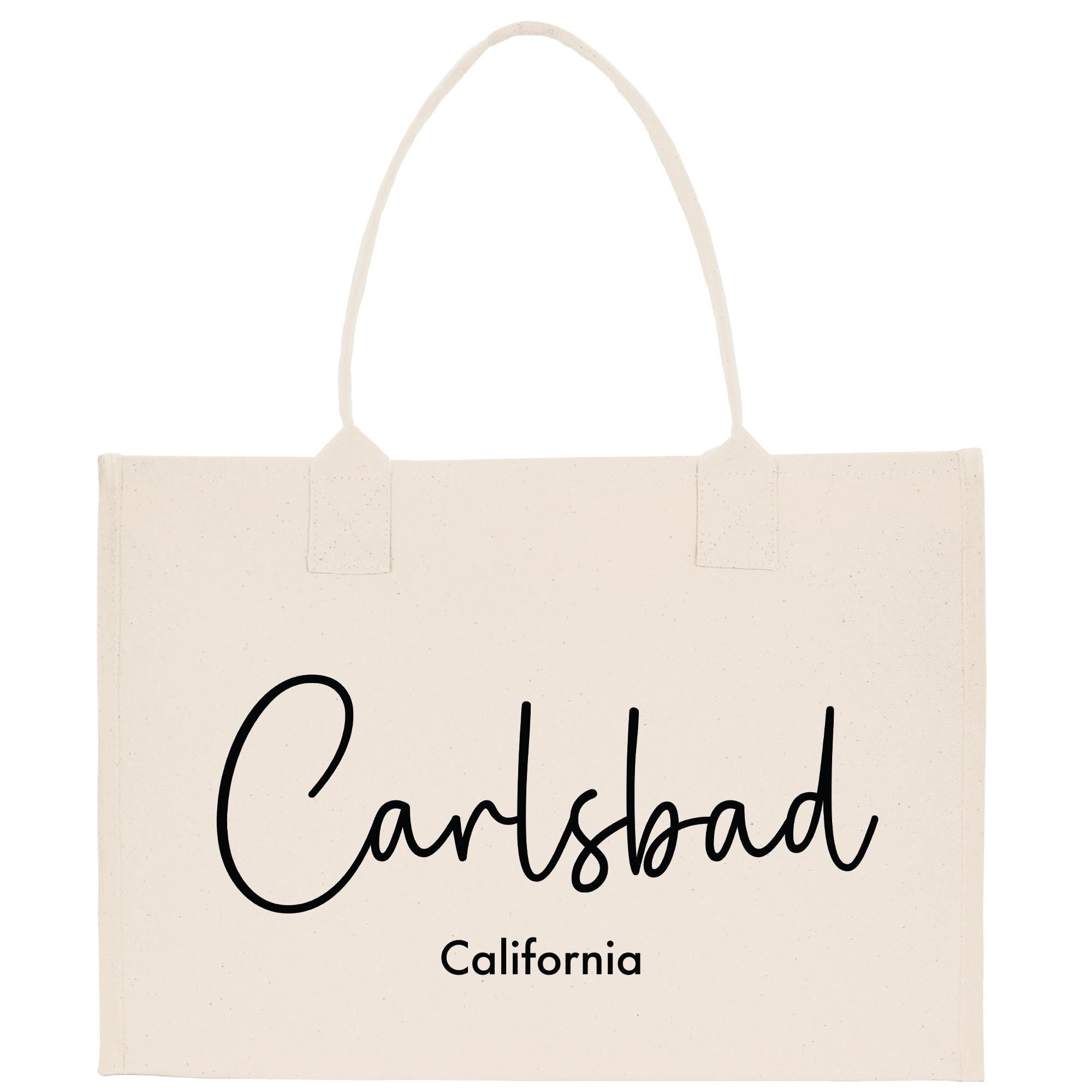 A beige canvas tote bag with the text &quot;Carlsbad, California&quot; printed on it.