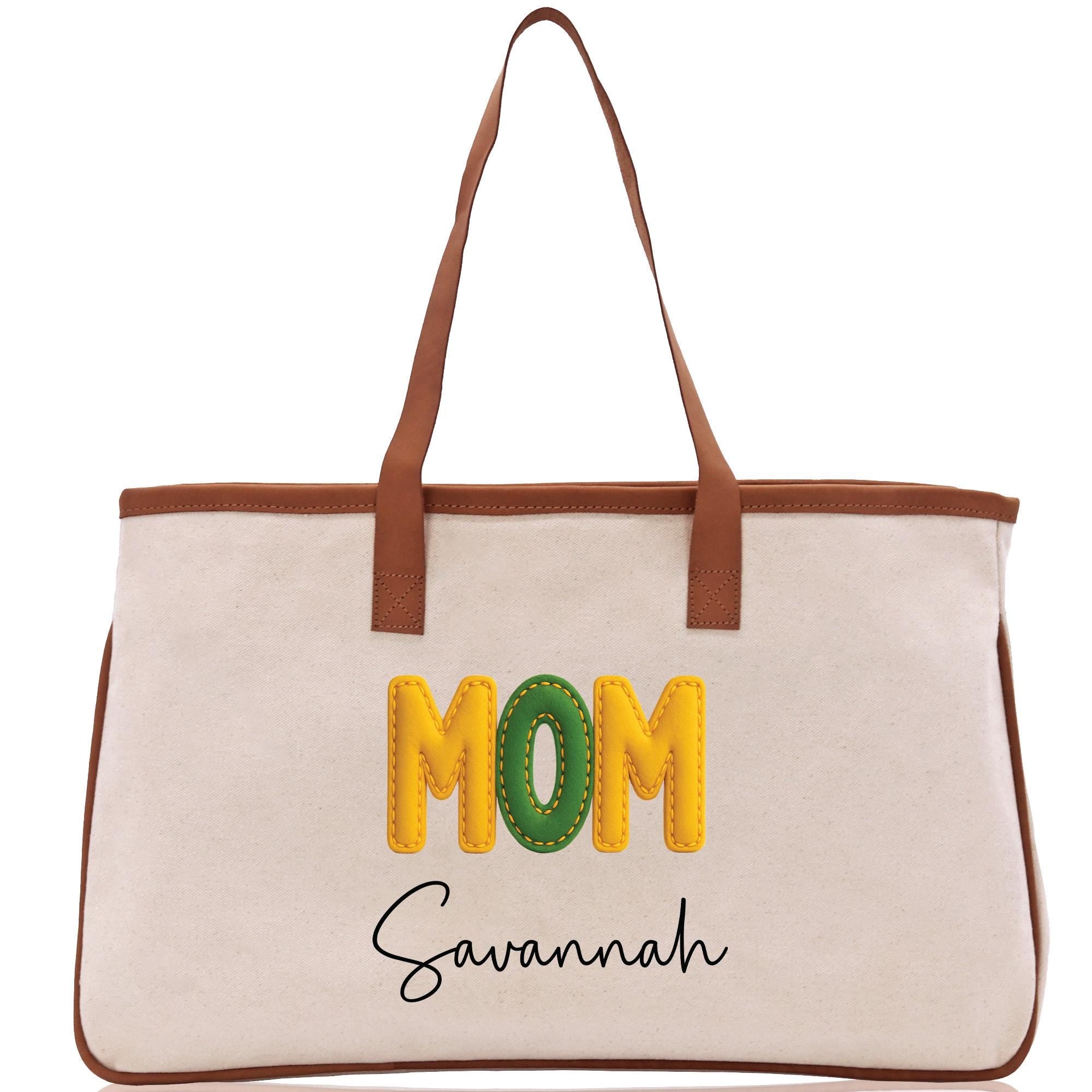A beige canvas tote bag with the word &quot;MOM&quot; printed in large yellow letters and the name &quot;Savannah&quot; written in smaller black letters below.