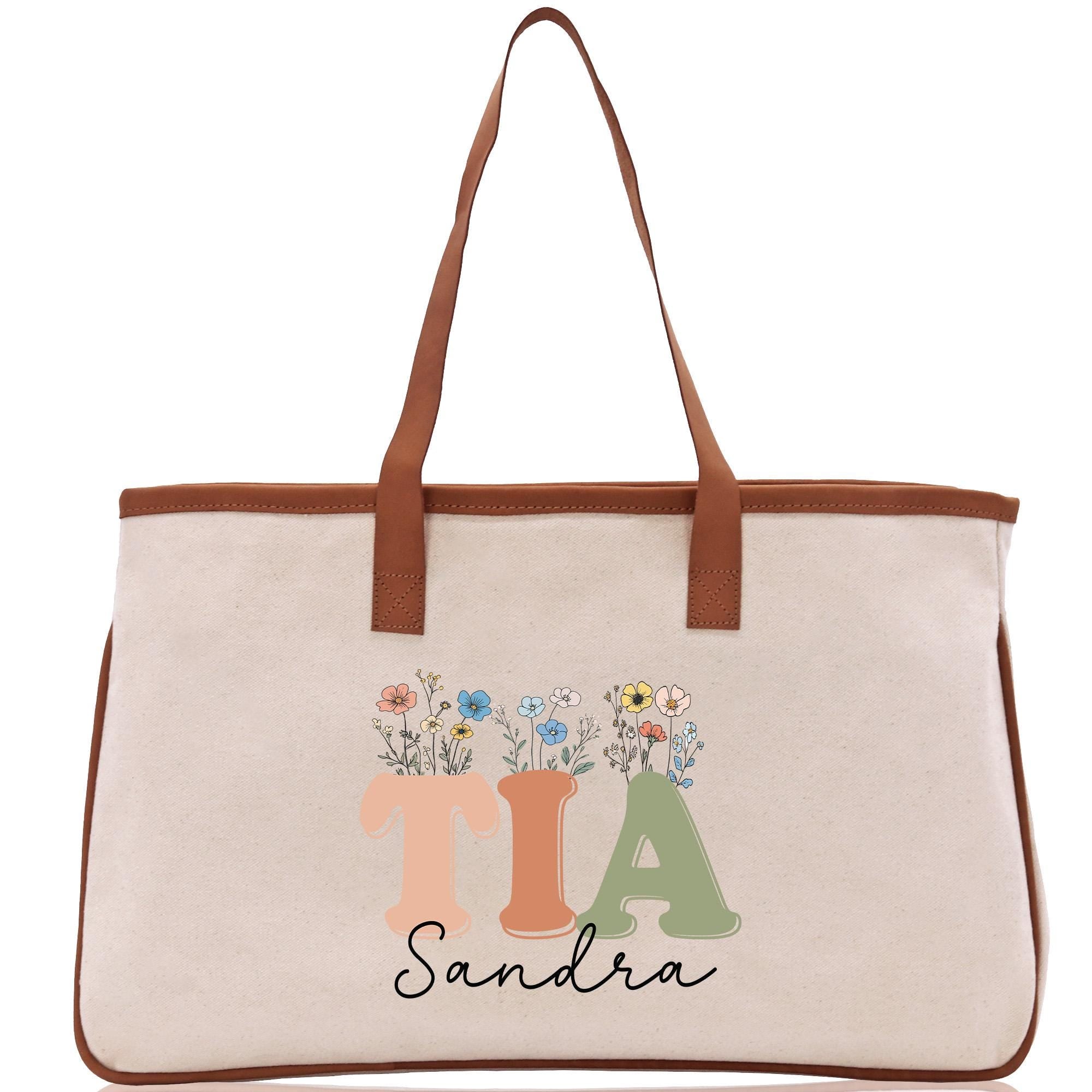 a white canvas bag with a brown leather handle