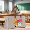 A beige tote bag with a cartoon pencil and apple design, featuring the text "Mrs. Roberts" on a tag attached to it.