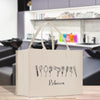 A white tote bag with a graphic design featuring various hair styling tools and the name "Recca" printed on it, placed on a wooden surface.
