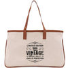 A beige canvas tote bag with a brown leather strap and a printed design on the front that reads 