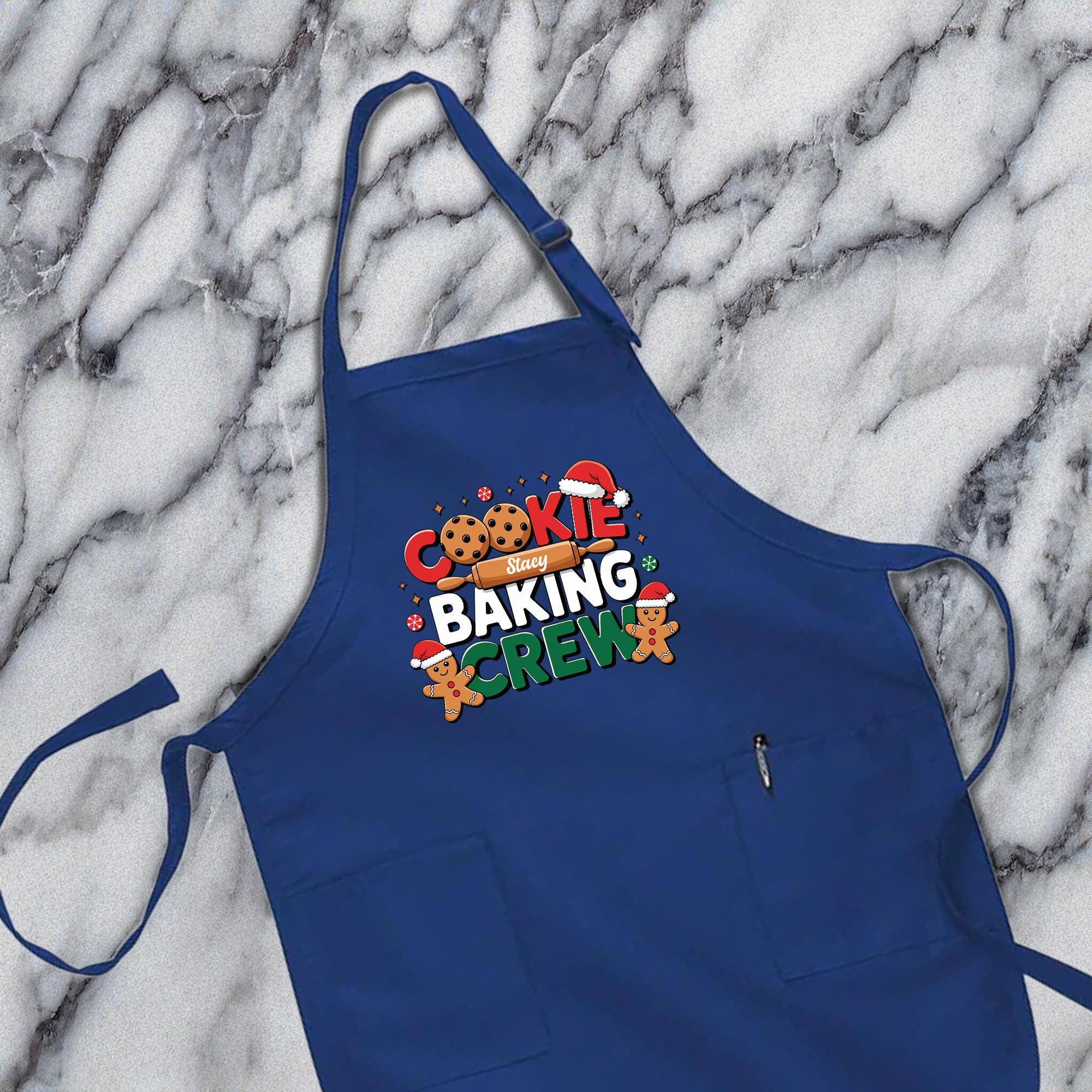 A blue apron with the text &quot;COOKIE BAKING CREW&quot; printed on it, along with images of cookies and gingerbread men.
