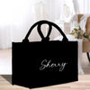 a black shopping bag sitting on top of a wooden floor