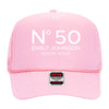 A pink trucker hat with the text "N°50 EMILY JOHNSON AUSTIN, TEXAS" printed on it.