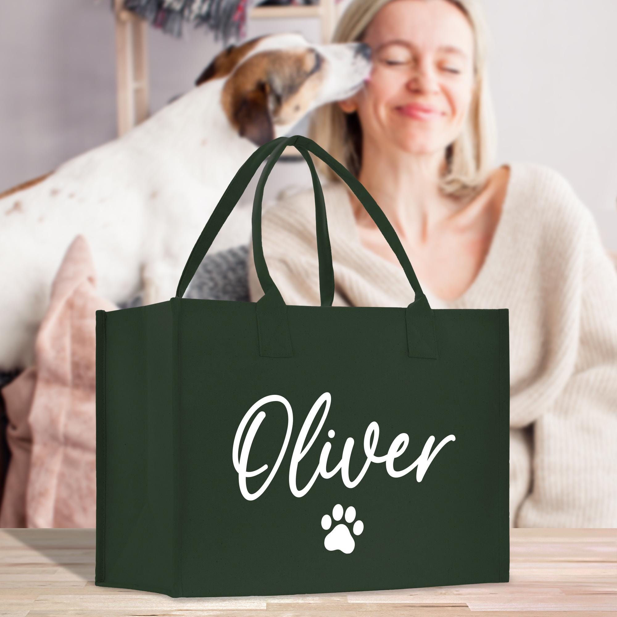 a woman holding a green shopping bag with a dog&#39;s paw on it