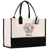 A beige tote bag with a black handle and a colorful, personalized name tag attached.
