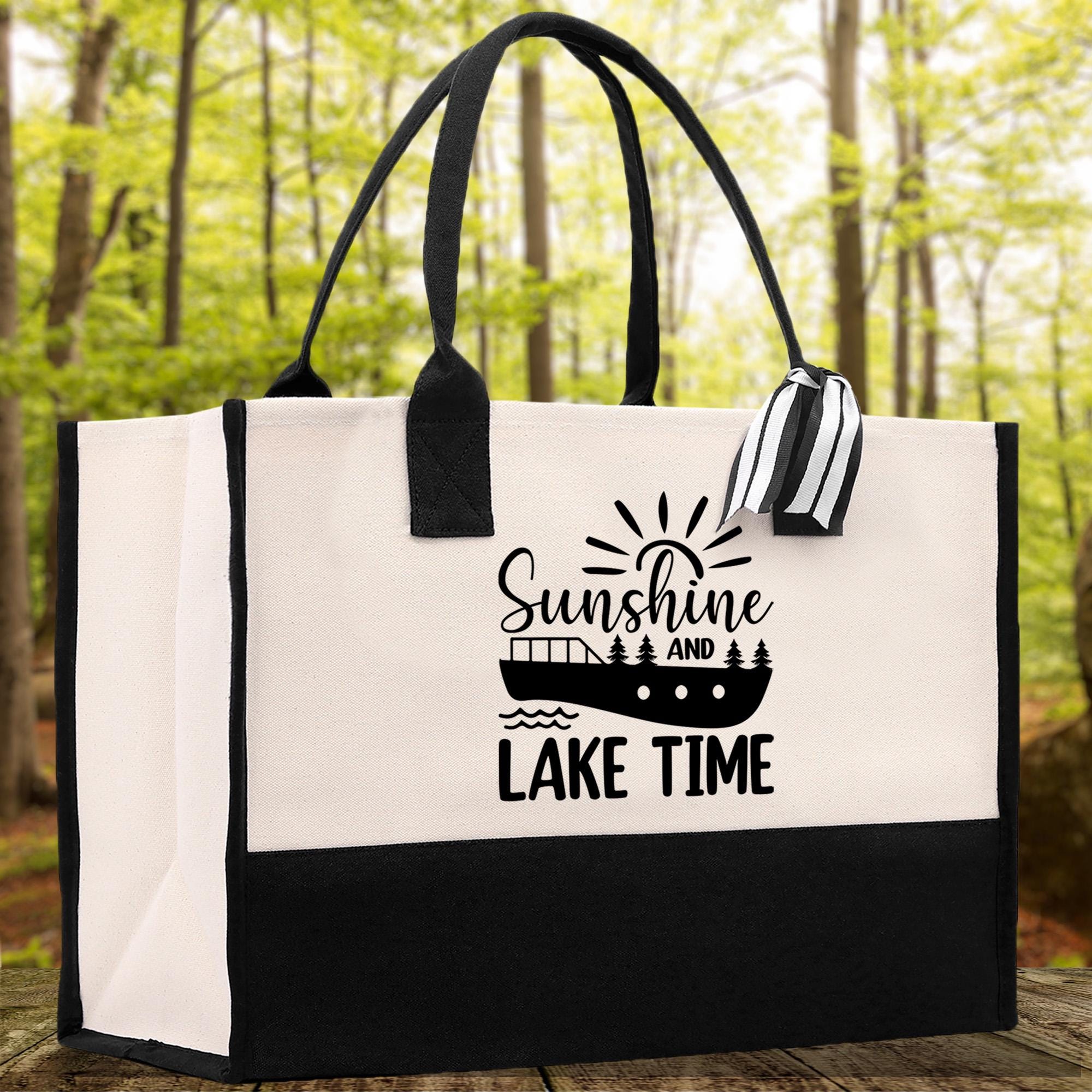 A black and white tote bag with a printed design on it, featuring a boat and the text "Sunshine and LAKE TIME".