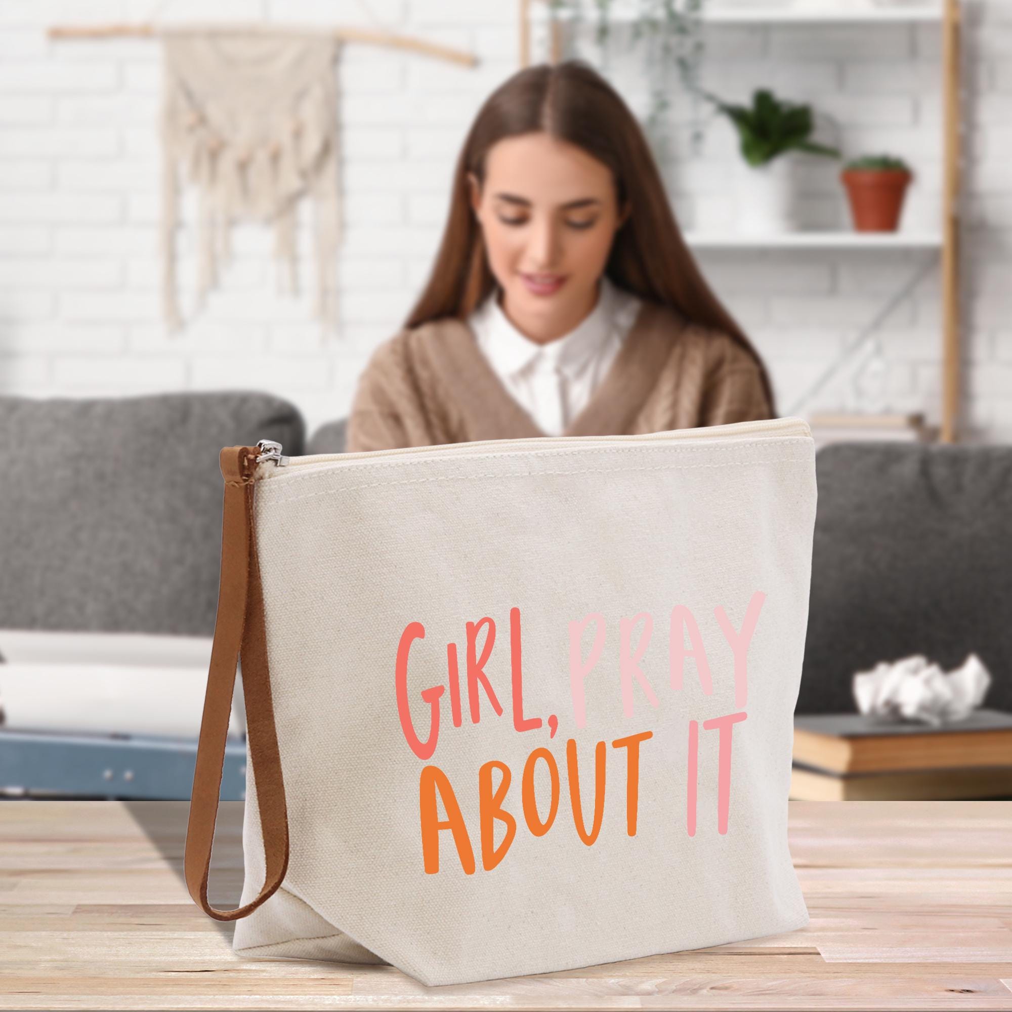 a woman sitting at a table with a bag that says girl pray about it