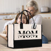 a woman sitting on a couch next to a woman holding a black and white bag