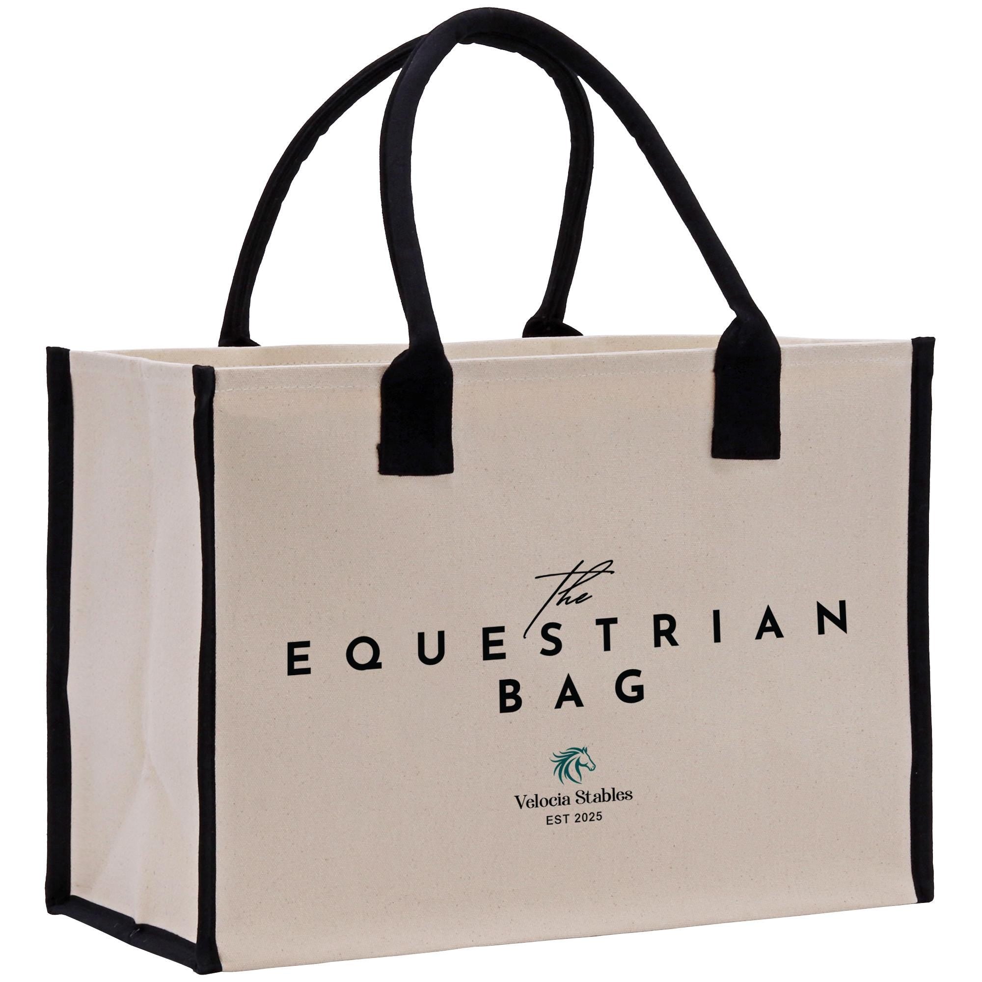 The image is a beige canvas tote bag with black handles and trim, featuring the text &quot;The Equestrian Bag&quot; and &quot;Valerie Stables EST 2026&quot; printed on it.