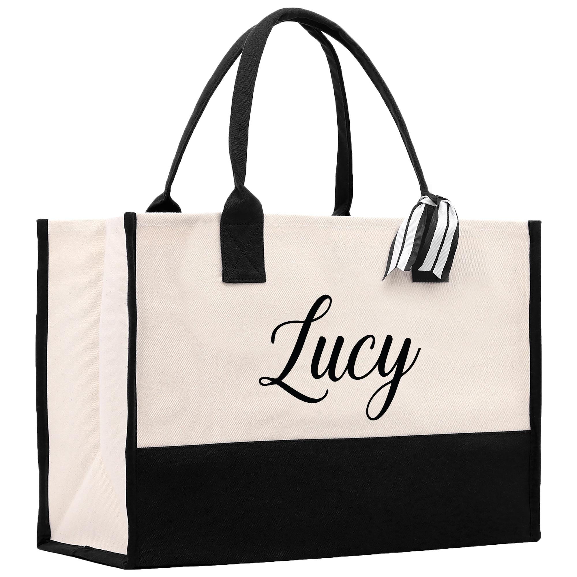 A large tote bag with a black and white color scheme. The bag has a name tag attached to it, and the name &quot;Lucy&quot; is printed on the front in a cursive font.