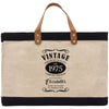 A beige tote bag with a black trim and leather handles, featuring a vintage-style design with text and graphics.