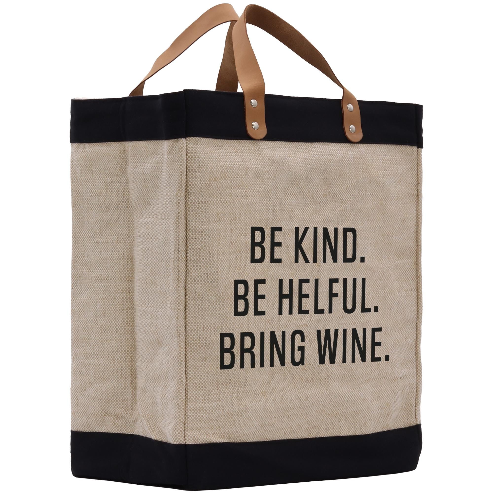 A beige tote bag with black trim and leather handles, featuring a printed message on the front that says &quot;Be kind. Be helpful. Bring wine.&quot;