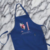 A blue apron with a floral design and the text "MONICA GREEN" printed on it, placed on a marble surface.
