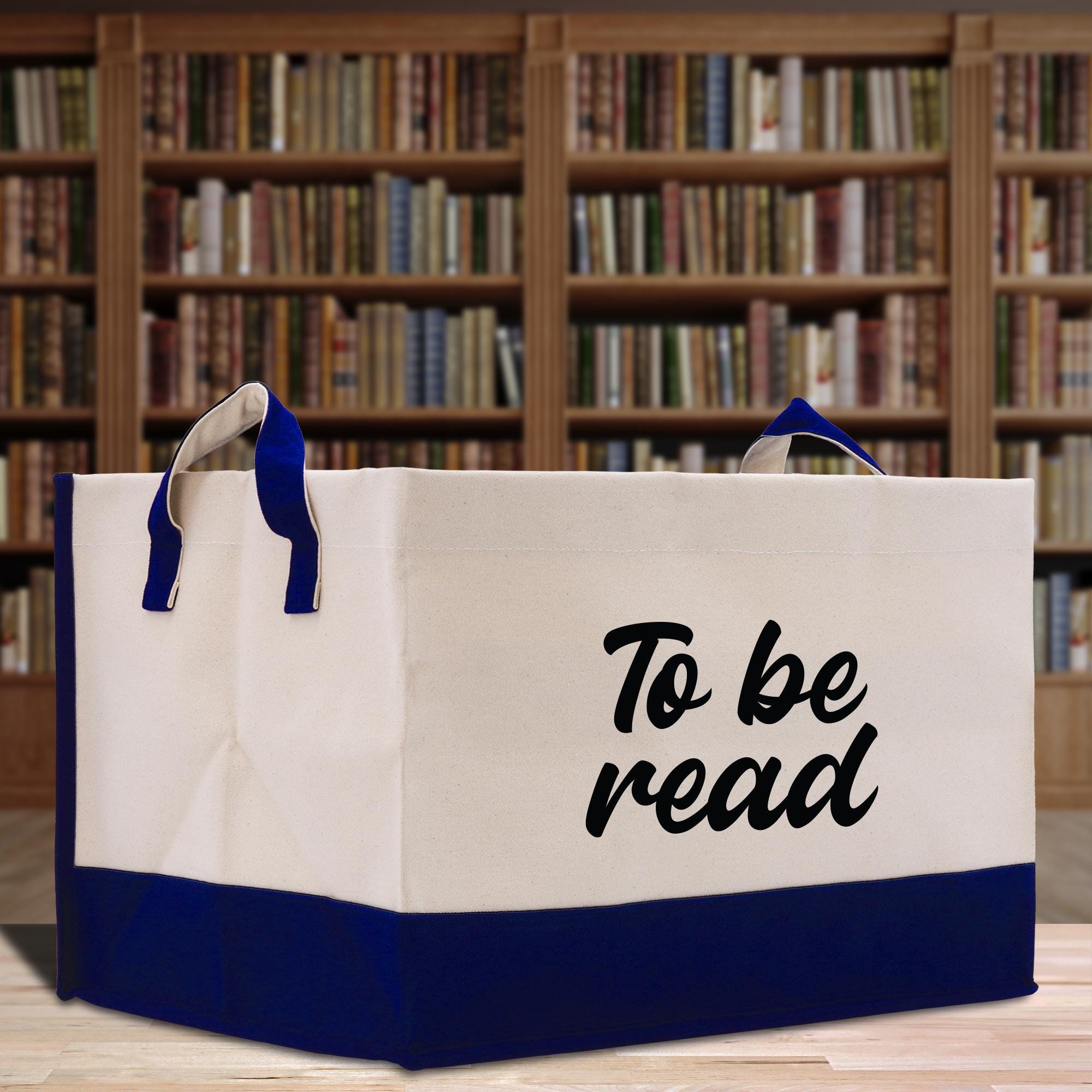 a to be read bag sitting on a table in front of a bookshelf