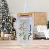 a glass with a straw in front of a christmas tree