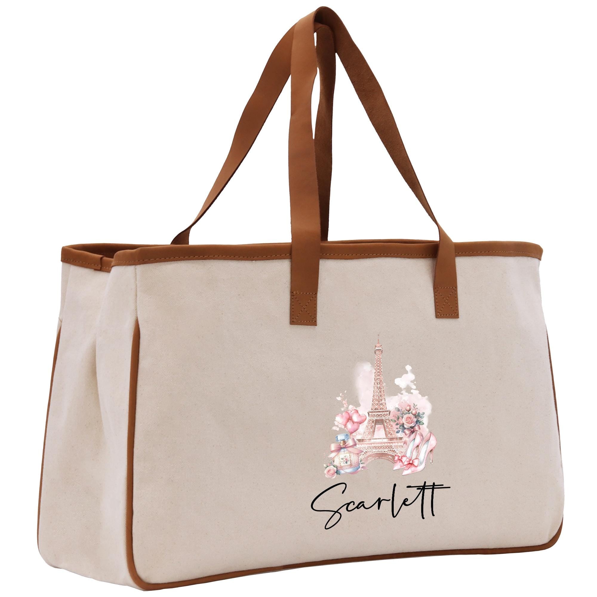A beige canvas tote bag with a brown handle and a printed image of the Eiffel Tower on it.