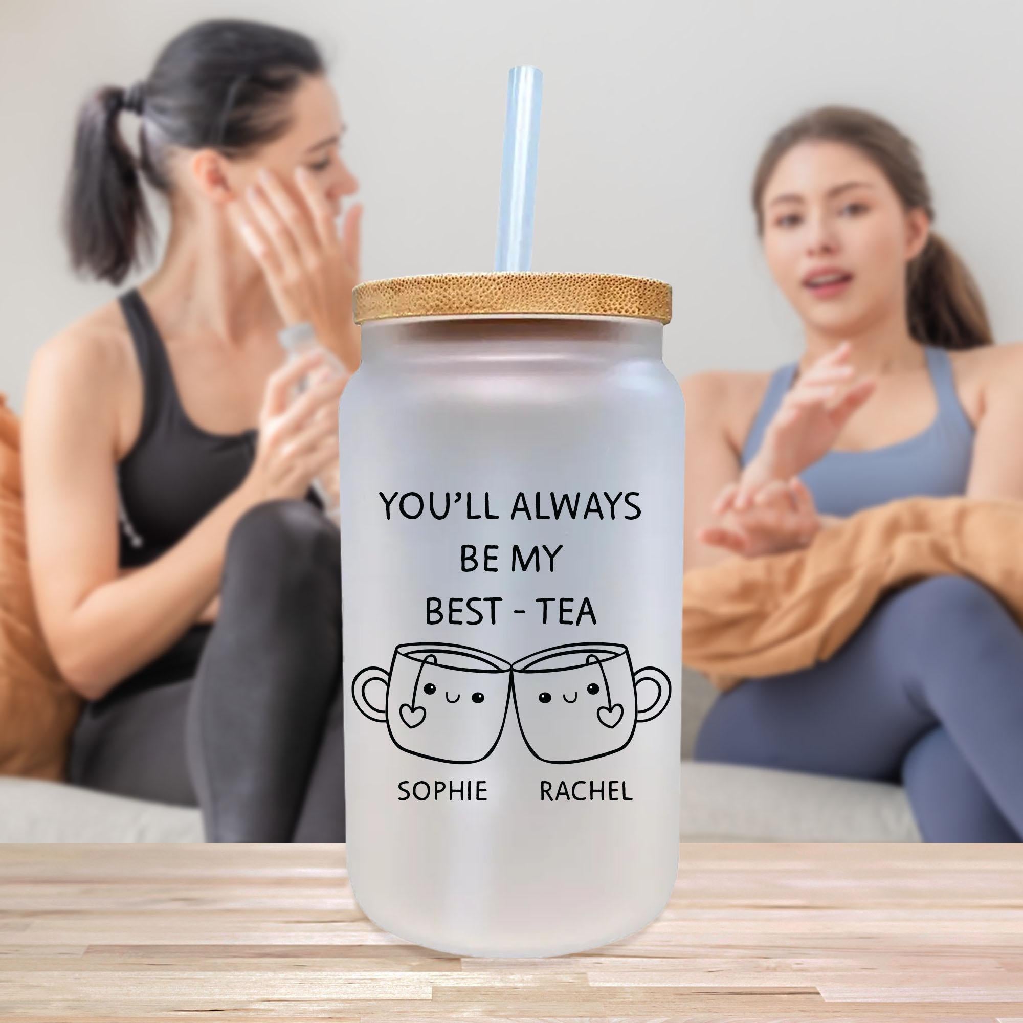 two women sitting on a couch with a drink in front of them